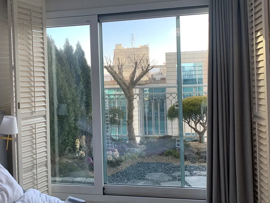 거실 발코니 창 너머로 정원과 인접 건물이 보이는 시공 전 사진