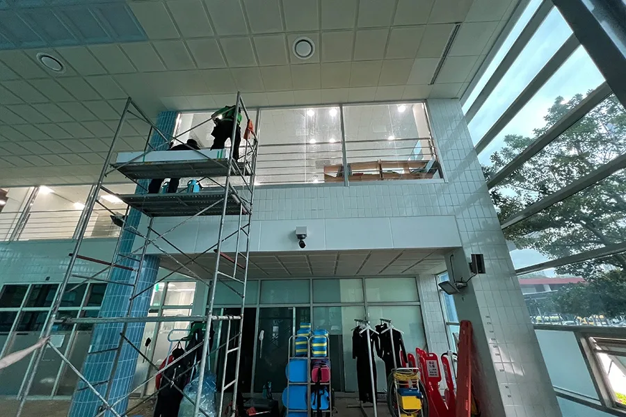 체육관 내부 높은 층고와 비계 위 작업자가 함께 보이는 사진