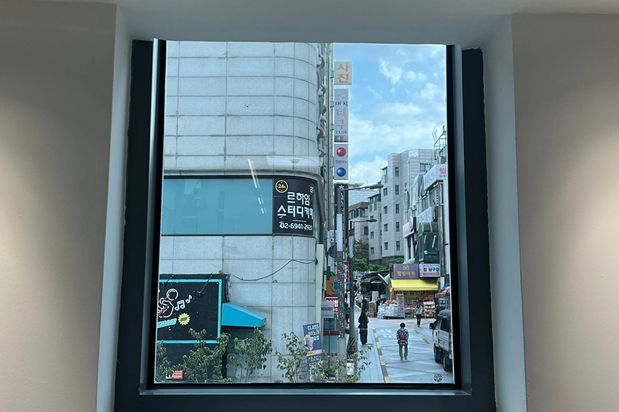 시공 전 계단실 통유리 창밖으로 거리 상가 간판이 그대로 비치는 사진