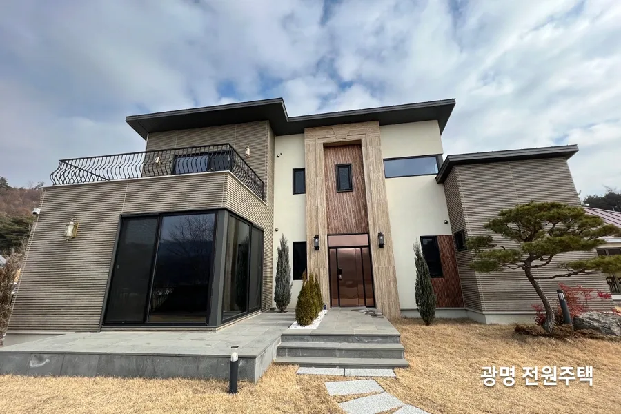 모서리 통유리창 안쪽으로 텔레비전과 소파가 있는 거실 내부 사진