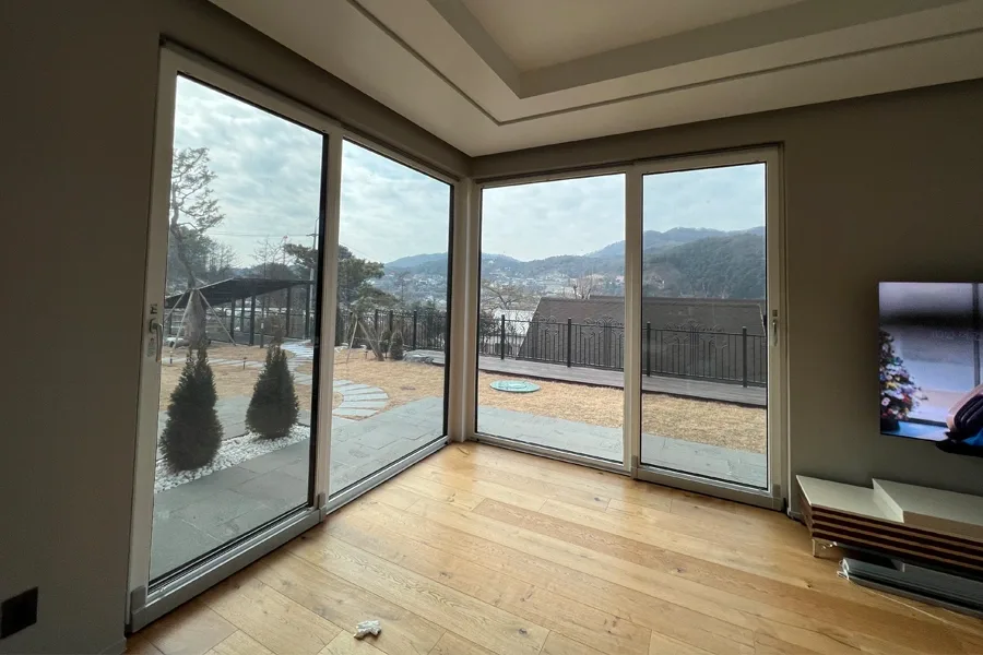거실 코너 통유리창 밖으로 산이 보이는 사진