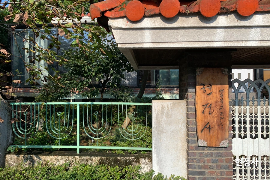 사찰 한옥 별채 출입구, 나무 현판과 통유리 창이 함께 보이는 사진
