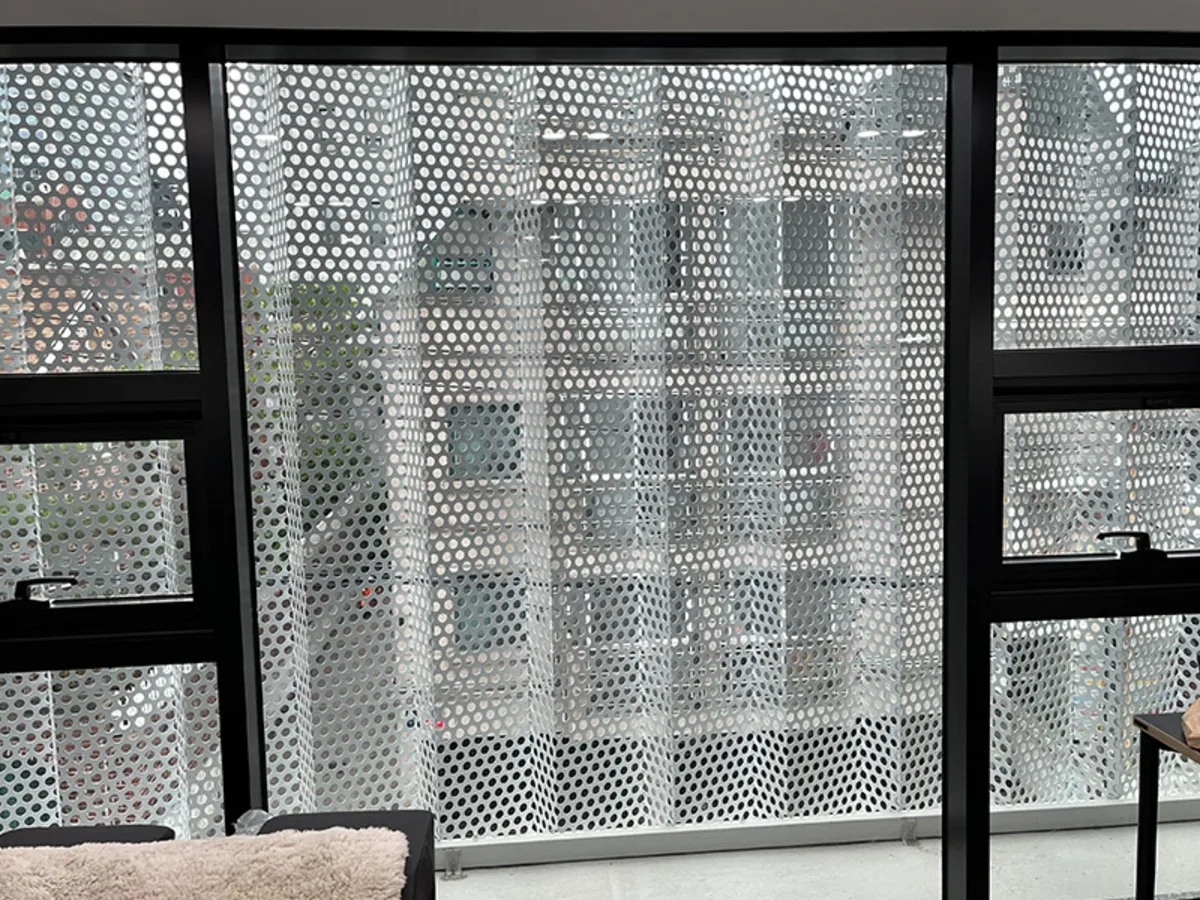 펫케어센터 창가에 설치된 펀칭 메탈 스크린 너머로 인근 건물이 비치는 시공 전 사진