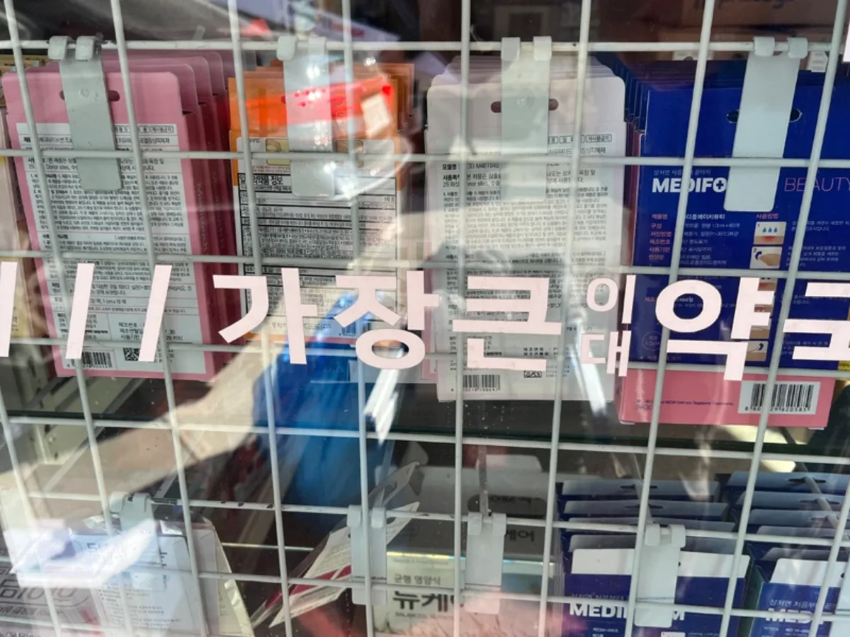 약국 진열창 안쪽으로 의약외품 상자가 촘촘히 진열된 시공 전 사진