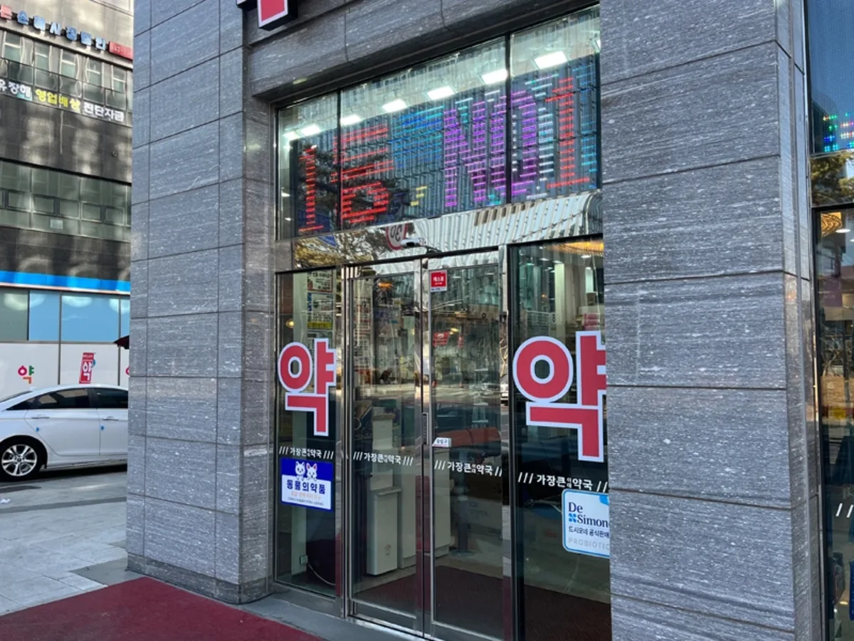 약국 출입문 손잡이 주변 유리에 안내 문구가 부착된 클로즈업 사진