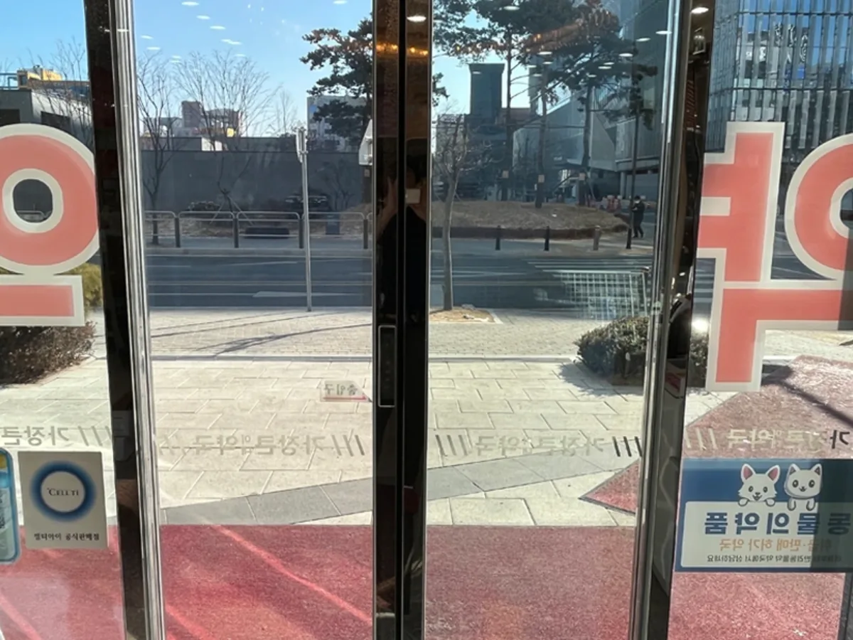 마주보는 두 개의 상가 출입문 유리에 거리 풍경이 비치는 사진